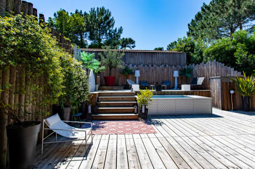 Terrasse de jardin spacieuse de la villa La Loge Du Bassin à Lège Cap Ferret avec terrasse en bois, transats et pins