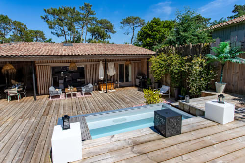 Villa moderne avec terrasse en bois, petite piscine, transats et bâtiments de villégiature entourés de pins à La Loge Du Bassin