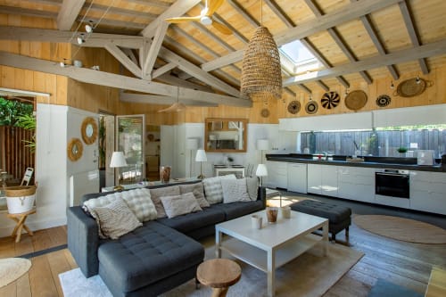 Salon moderne avec cuisine ouverte, canapé sectionnel noir et poutres en bois à La Loge Du Bassin, Lège Cap Ferret