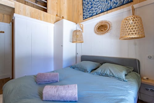 Chambre avec literie bleue, luminaires suspendus tressés et mobilier blanc moderne à Villa Biscouette, Lège Cap Ferret
