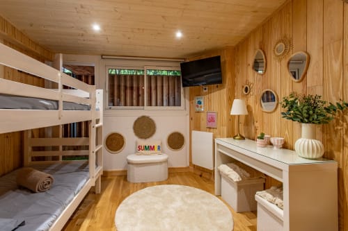 Chambre cosy en bois à La Loge Du Bassin avec lits superposés, bureau blanc, tapis rond et vue sur le jardin à Lège Cap Ferret
