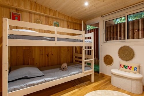 Chambre lumineuse avec lits superposés en bois à la Villa Biscouette à Lège Cap Ferret, vue sur le jardin, décoration tressée et équipements modernes.