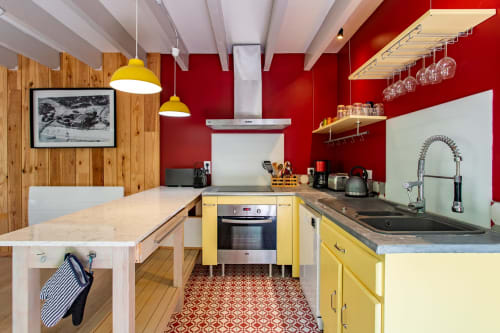 Cuisine moderne avec placards jaunes, murs rouges et accents en bois à la Villa Cap à l'Ouest à Lège-Cap-Ferret
