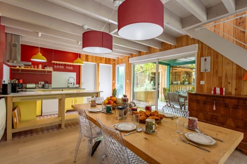 Cuisine ouverte et salle à manger moderne à la Villa Cap à l'Ouest à Lège-Cap-Ferret avec suspensions rouges et vue sur le jardin