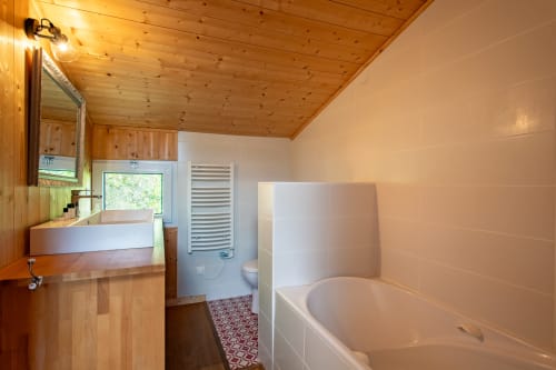 Salle de bain avec plafond en bois, baignoire blanche, lavabo et toilettes à la Villa Cap à l'Ouest à Lège-Cap-Ferret