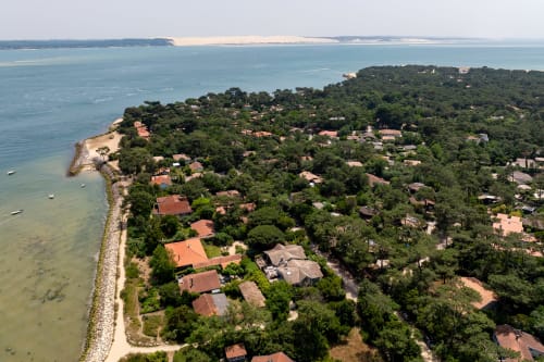 Vue aérienne de la villa La Loge Du Bassin à Lège-Cap-Ferret, entourée d'arbres et du Bassin d'Arcachon