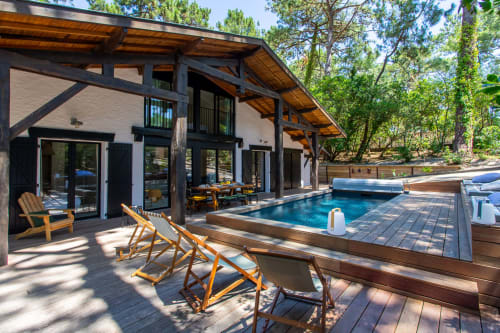 Espace piscine moderne de La Loge Du Bassin avec bassin chauffé, terrasse en bois, transats et design épuré noir et blanc