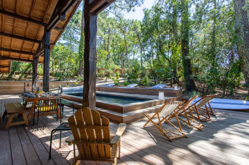 Terrasse en bois avec transats et espace repas donnant sur piscine chauffée entourée de pins à La Loge Du Bassin
