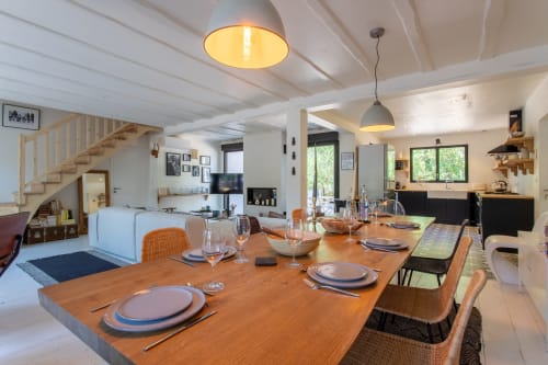 Espace ouvert de repas et séjour à la villa La Loge Du Bassin avec table en bois, chaises tressées et cuisine