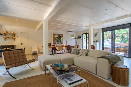 Salon contemporain de la villa La Loge Du Bassin avec canapé beige, cheminée et portes vue piscine à Lège-Cap-Ferret