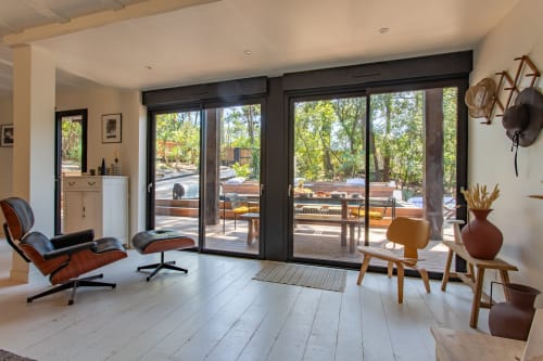 Villa moderne avec baies vitrées ouvertes sur la piscine, mobilier mi-siècle, sols blancs et cadre boisé
