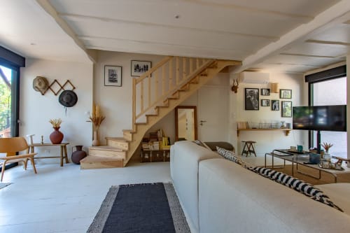 Salon de villa moderne avec escalier en bois, canapé beige, télévision écran plat et décoration contemporaine à La Loge Du Bassin