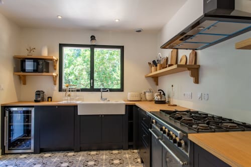 Cuisine contemporaine aux placards noirs, plan de travail et étagères en bois à la villa La Loge Du Bassin à Lège-Cap-Ferret