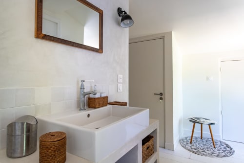 Salle de bain moderne avec vasque blanche, paniers de rangement tissés et miroir à cadre bois à La Loge Du Bassin
