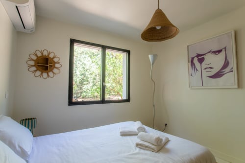 Chambre lumineuse de la villa Pins d'Agalis à La Loge Du Bassin, Lège-Cap-Ferret, avec lit blanc, lampe suspendue tissée et jardin