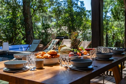 Table de salle à manger en plein air à la villa La Loge Du Bassin à Lège-Cap-Ferret avec viennoiseries fraîches, fruits et couverts