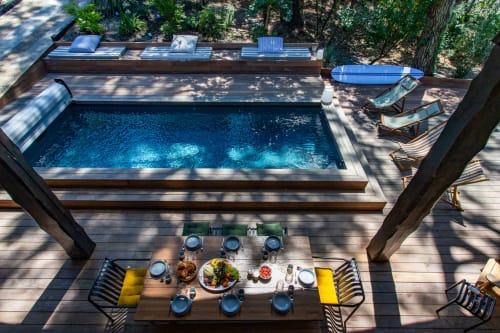 Vue aérienne de la piscine de la villa La Loge Du Bassin avec table de repas, mets gastronomiques et chaises longues sur terrasse en bois