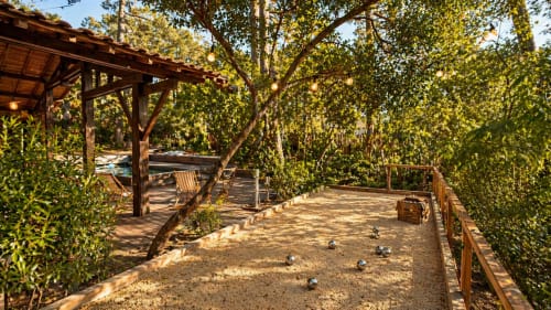 Terrain de pétanque à la villa La Loge Du Bassin avec pergola en bois, verdure luxuriante et terrasse de piscine à Lège-Cap-Ferret