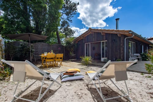 Jardin de villa en bord de mer avec chaises longues, salon de jardin jaune sous pergola et terrasse en bois à La Loge Du Bassin