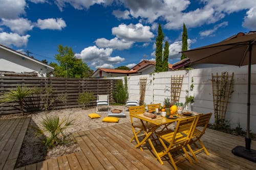 Terrasse ensoleillée de la villa La Palombiere avec salon de jardin jaune, transats et murs blancs à Andernos-les-Bains