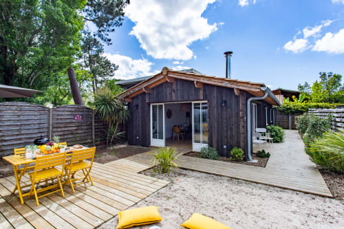 Villa moderne en bois sombre à La Loge Du Bassin à Andernos-les-Bains avec mobilier de jardin jaune et vue sur le jardin