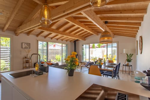 Cuisine ouverte et séjour de la villa La Palombière avec poutres en bois apparentes, vue sur le jardin et équipements modernes