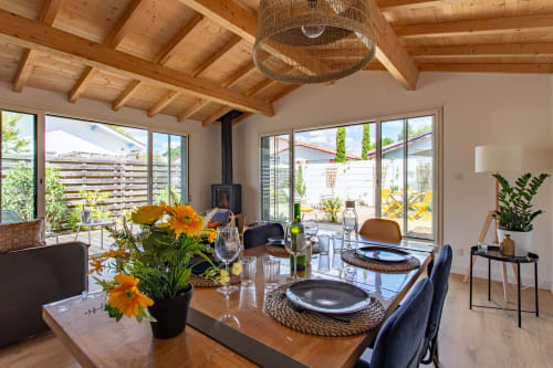 Salle à manger moderne aux poutres en bois, vue sur jardin et terrasse extérieure de la villa La Palombière, Andernos-les-Bains