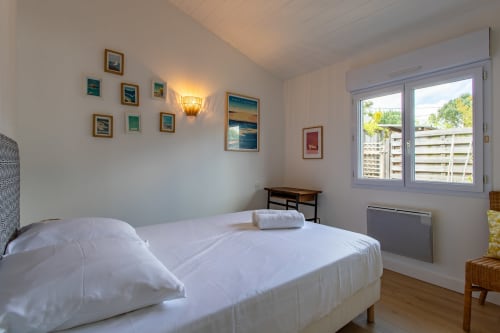 Chambre lumineuse avec linge de lit blanc et vue sur le jardin à la villa La Palombière à Andernos-les-Bains