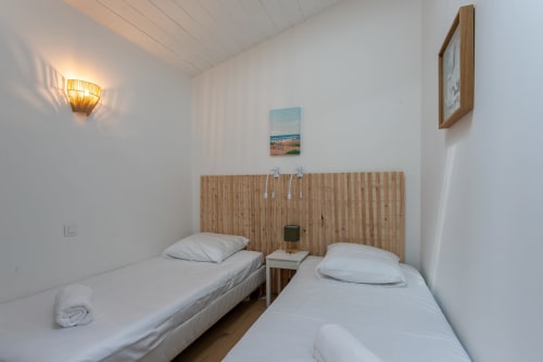 Deux lits jumeaux aux draps blancs et tête de lit en bois de la villa La Palombière à La Loge Du Bassin, Andernos-les-Bains