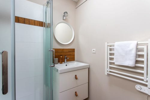 Salle de bains moderne de la villa La Loge Du Bassin avec vasque blanche, miroir rétroéclairé et porte-serviettes chauffant