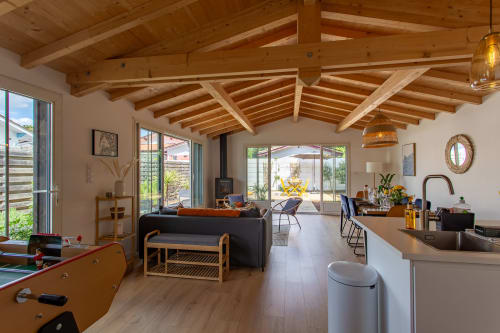 Intérieur de villa ouverte à La Loge Du Bassin avec poutres apparentes, cuisine, salle à manger et vue sur le jardin