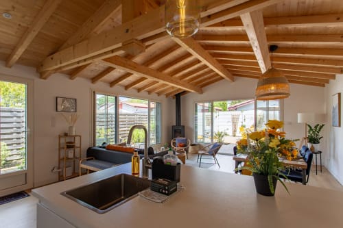 Villa moderne à La Loge Du Bassin avec poutres apparentes, îlot de cuisine, cheminée et vue sur le jardin
