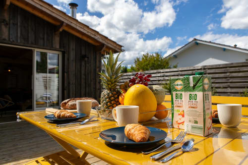 Petit-déjeuner en plein air à la villa La Palombière à Andernos-les-Bains avec table jaune, viennoiseries, fruits frais et produits bio