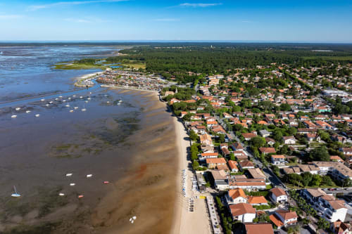 Vue aérienne d'Andernos-les-Bains avec bateaux dans la baie, plage et quartiers résidentiels arborés