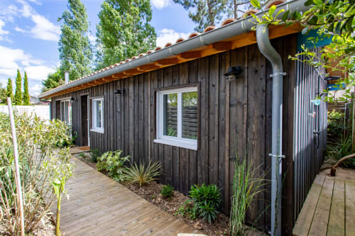 Villa moderne en bois sombre à La Loge Du Bassin, Andernos-les-Bains avec terrasse en bois, fenêtres blanches et jardin luxuriant