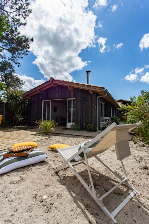 Villa en bois moderne avec plage de sable, transats et coussins jaunes à La Palombière, Andernos-les-Bains