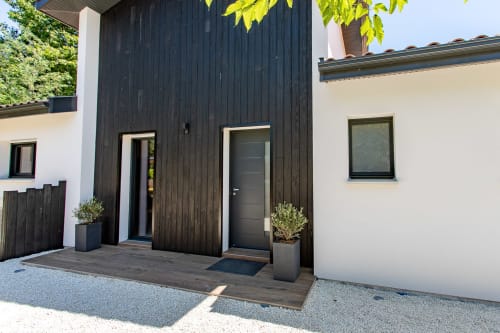 Entrée élégante de villa moderne avec bardage bois noir et murs blancs à La Loge Du Bassin, Andernos-les-Bains