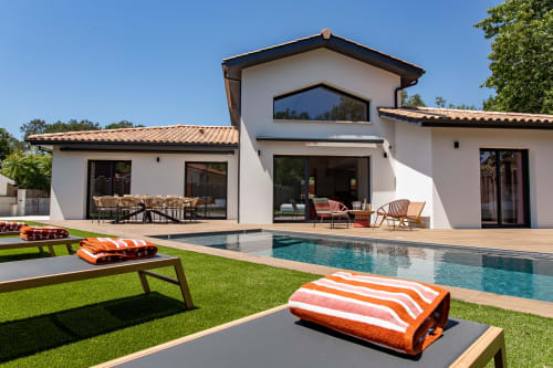 Villa moderne avec piscine chauffée, transats orange et architecture blanche aux tuiles terre cuite à Andernos-les-Bains