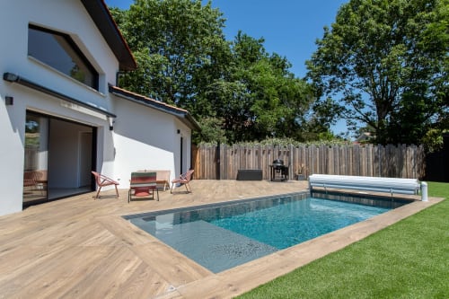 Piscine chauffée de la Villa la Parenthèse avec terrasse en bois, maison blanche moderne, transats et clôture en bois à Andernos-les-Bains