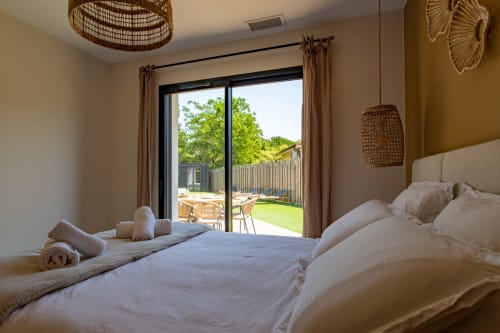 Chambre moderne à la Villa la Parenthèse avec literie blanche, ouvrant sur vue jardin et piscine à Andernos-les-Bains