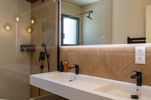 Salle de bain moderne avec double vasque, panneautage géométrique en bois et douche vitrée à la Villa la Parenthèse de La Loge Du Bassin