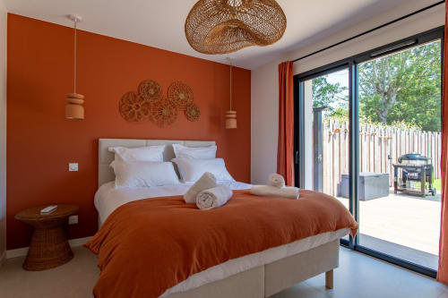 Chambre moderne à la Villa la Parenthèse à Andernos-les-Bains avec mur accent orange brûlé, literie blanche et suspension tissée