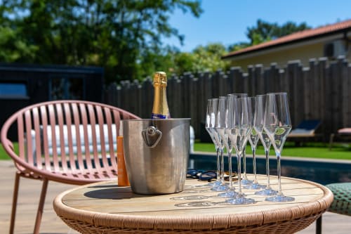 Bouteille de champagne dans un seau à glaçons avec flûtes sur table extérieure, vue sur la piscine à la villa La Loge Du Bassin