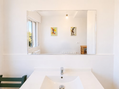 Espejo de baño moderno y lavamanos blanco en la casita Nova Anduriña en Holibai, Gondomar con obra de arte exhibida arriba