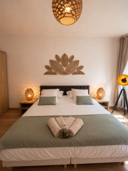 Stylish Studio Deluxe bedroom at Le Clos Androne, Sisteron, with decorative leaf wall art, golden pendant light, and