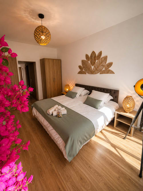 Stylish Studio Deluxe bedroom at Le Clos Androne, Sisteron, with king bed, golden pendant lights, and magenta flowers