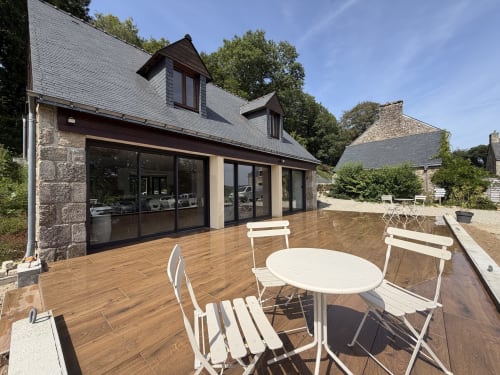 Élégante réception au Domaine de Lann Kerhuerh avec terrasse en bois, mobilier blanc et architecture en pierre