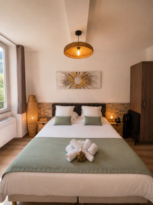 Modern studio bedroom at Le Clos Androne hotel in Sisteron with queen bed, woven pendant light, and mountain views
