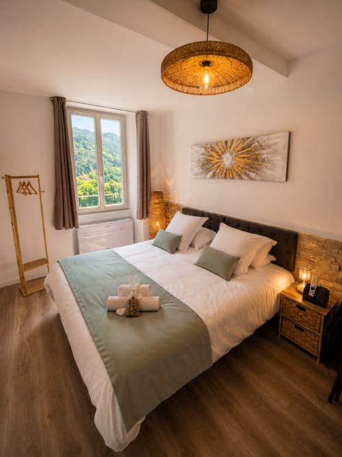 Modern studio apartment bedroom at Le Clos Androne, Sisteron, with mountain views, wooden furnishings, and contemporary décor