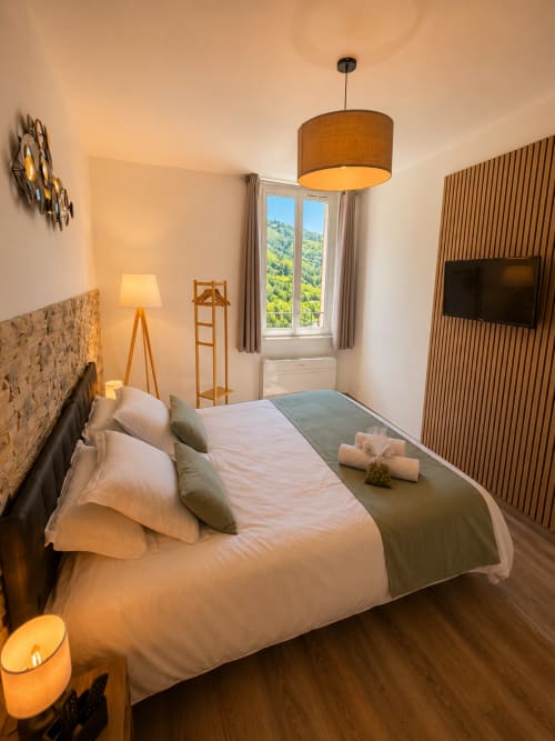 Modern hotel bedroom at Le Clos Androne in Sisteron with mountain views, wooden furnishings, and comfortable bedding